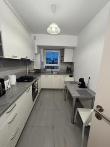 a kitchen with white cabinets and a table and a window at Luxury Avantgarden apartament in Braşov