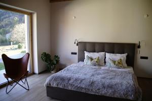 Un dormitorio con una cama, una silla y una ventana en MALIA - Alpine Hideaway, en Pertisau