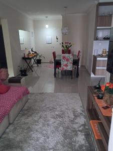 a living room with a couch and a dining room at Apto Pe na areia # Piscina e Churrasqueira in Mongaguá +7 photos