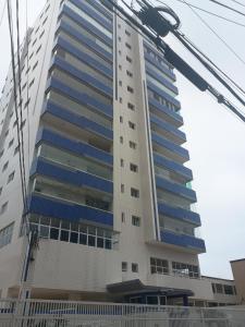 a tall building with blue windows and a street light at Apto Pe na areia # Piscina e Churrasqueira in Mongaguá