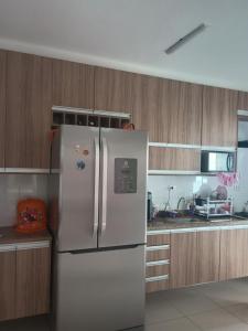 a white refrigerator in a kitchen with wooden cabinets at Apto Pe na areia # Piscina e Churrasqueira in Mongaguá