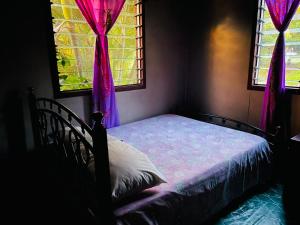 a bedroom with a bed and two windows with pink curtains at Nukuwasiga homestay in Soso