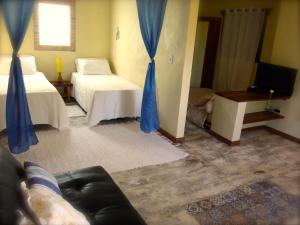 una sala de estar con dos camas y un sofá en Pousada do Sonho, en São Miguel dos Milagres