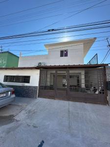 a white house with a brown garage door at Departamentos Mateo'S 655 in Ciudad Acuña