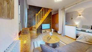 a living room with a couch a table and a tv at Au pied du Haut Koenigsbourg 2 in Saint-Hippolyte