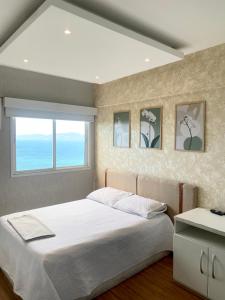 a bedroom with a large bed and a window at Porto Real Resort Apto luxo de frente ao mar in Mangaratiba