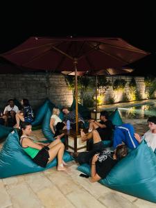 a group of people sitting on blue pillows under an umbrella at Jancoox Hostel in Kuta Lombok