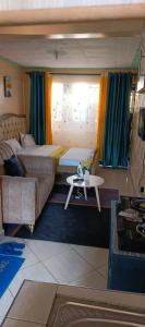a bedroom with two beds and a couch and a table at Studios in roysambu in Nairobi