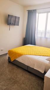 BuenavistaKira Apartahotel的卧室里有一张大床，床上铺着黄色毯子
