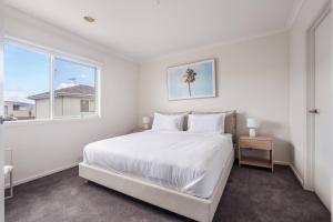 een witte slaapkamer met een groot bed en een raam bij Foreshore Escape - Beachside Comfort near Dining in Safety Beach