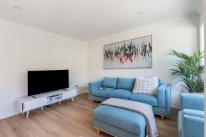 een woonkamer met een blauwe bank en een tv bij Foreshore Escape - Beachside Comfort near Dining in Safety Beach