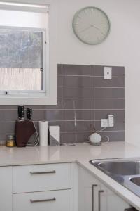 een keuken met een klok aan de muur en een wastafel bij Foreshore Escape - Beachside Comfort near Dining in Safety Beach