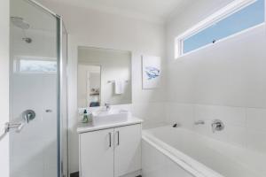 een witte badkamer met een wastafel en een douche bij Foreshore Escape - Beachside Comfort near Dining in Safety Beach +27 foto's