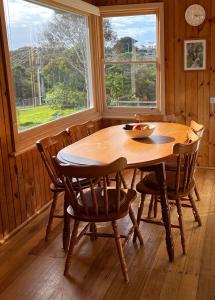 a wooden table and chairs in a room with a window at Nunyara - BYO Linen in Aireys Inlet