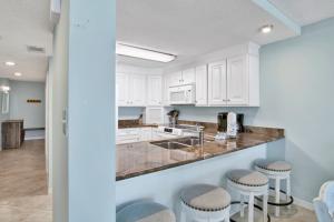 a kitchen with white cabinets and bar stools at Buena Vista 102 in Gulf Shores +26 photos