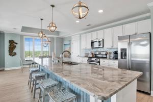 a kitchen with a large marble counter top with stools at The Wharf 701 in Orange Beach +42 photos