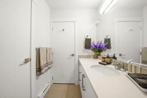 2 bed Suburban Oasis in Surrey في سوري: حمام أبيض مع حوض ومرآة +20 صورة