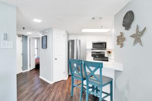 a kitchen with a blue chair and a kitchen with a refrigerator at Phoenix III 3038 in Orange Beach