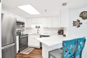 a white kitchen with a refrigerator and two blue chairs at Phoenix III 3038 in Orange Beach +31 photos