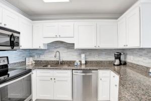 a white kitchen with white cabinets and a sink at Phoenix East II 2154 in Orange Beach +28 photos