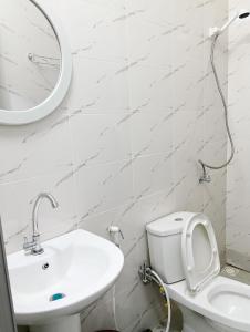 ein Badezimmer mit Waschbecken, Toilette und Spiegel in der Unterkunft Royal Comfort Lodge in Thiès