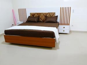 ein Schlafzimmer mit einem großen Bett mit einem hölzernen Kopfteil in der Unterkunft Royal Comfort Lodge in Thiès