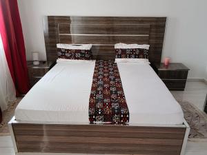 ein Schlafzimmer mit einem Bett mit hölzernem Kopfteil in der Unterkunft Royal Comfort Lodge in Thiès