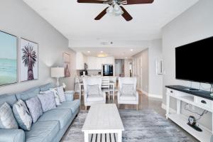 a living room with a blue couch and a flat screen tv at Lighthouse 1713 in Gulf Shores