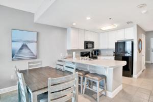 a kitchen with a table and chairs and a refrigerator at Lighthouse 1713 in Gulf Shores