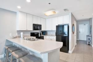 a kitchen with white cabinets and a black refrigerator at Lighthouse 1713 in Gulf Shores +28 photos