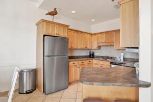 a kitchen with wooden cabinets and a stainless steel refrigerator at Phoenix V 014 in Orange Beach +25 photos