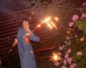 Eine Frau hält einen Regenschirm mit Wunderkerzen. in der Unterkunft Kawa Mountains Hakuba in Hakuba