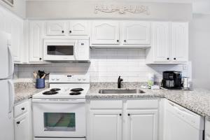 a white kitchen with white cabinets and a sink at Lei Lani M119 in Orange Beach