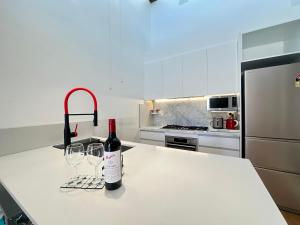 a bottle of wine and two wine glasses on a kitchen counter at Stylish 2BR Family-Friendly Retreat 4Guests Doncaster Westfield in Doncaster