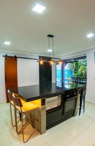 een keuken met een zwart aanrecht en een aantal stoelen bij O paraíso em Peruíbe Casa para até 25 pessoas in Peruíbe