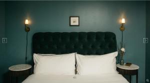 ein Bett mit einem großen schwarzen Kopfteil und zwei Tischen in der Unterkunft Hotel Emeline in Charleston