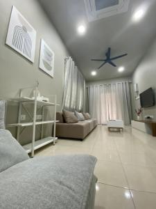 un soggiorno con un divano e un ventilatore a soffitto di Cozy Corner House, Bandar Utama a Gua Musang