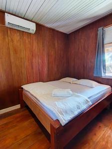 een slaapkamer met een bed in een houten wand bij Likat Surf House in Tua Pejat
