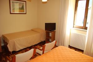 a small room with two beds and a television at Hotel Delle Alpi in Sondalo