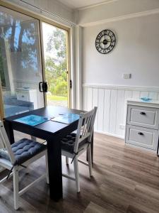 Kookaburra Retreat - Apartment في بكنهام: غرفة طعام مع طاولة وكراسي وساعة