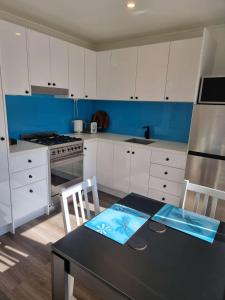 Kookaburra Retreat - Apartment في بكنهام: مطبخ بدولاب بيضاء وطاولة وكراسي سوداء