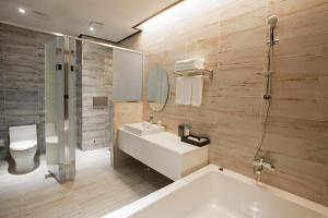 a bathroom with a tub and a sink and a toilet at CS Premier Hotel in Anyang