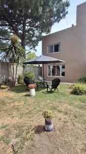 Un patio con dos sillas y una mesa con sombrilla. en Casa Saint Claire, en Santa Clara del Mar