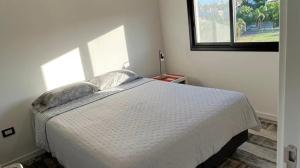 圣尼古拉斯Moderno departamento的一间卧室，有一张白色的床和一扇窗户