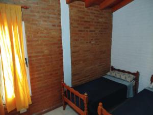 ein Schlafzimmer mit zwei Betten und einer Ziegelwand in der Unterkunft Shanti Cabañas in Mina Clavero