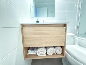 a bathroom with a sink and a toilet and towels at Departamento cerca de Cavancha Estacionamiento incluido in Iquique
