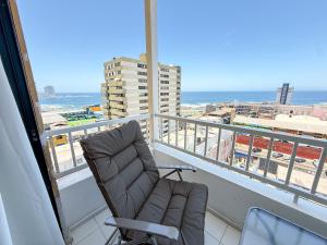 a chair on a balcony with a view of the ocean at Departamento cerca de Cavancha Estacionamiento incluido in Iquique