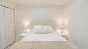 Un dormitorio blanco con una gran cama blanca con dos lámparas. en Florida Paradyse ll 5 min downtown Cozy Modern, en Fort Myers