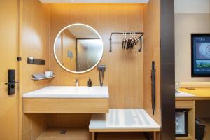 a bathroom with a sink and a mirror at JI Hotel Shenzhen Huaqiang North Huaqiang Road Subway Station in Shenzhen