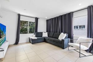 The Coastal Escape - Games & Vibes في غولد كوست: غرفة معيشة مع أريكة وبعض النوافذ